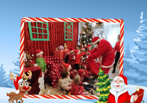 Dzieci ze Skrzatów ubrane na czerwono z Mikołajem na tle dekoracji przedstawiającej domek Mikołaja
